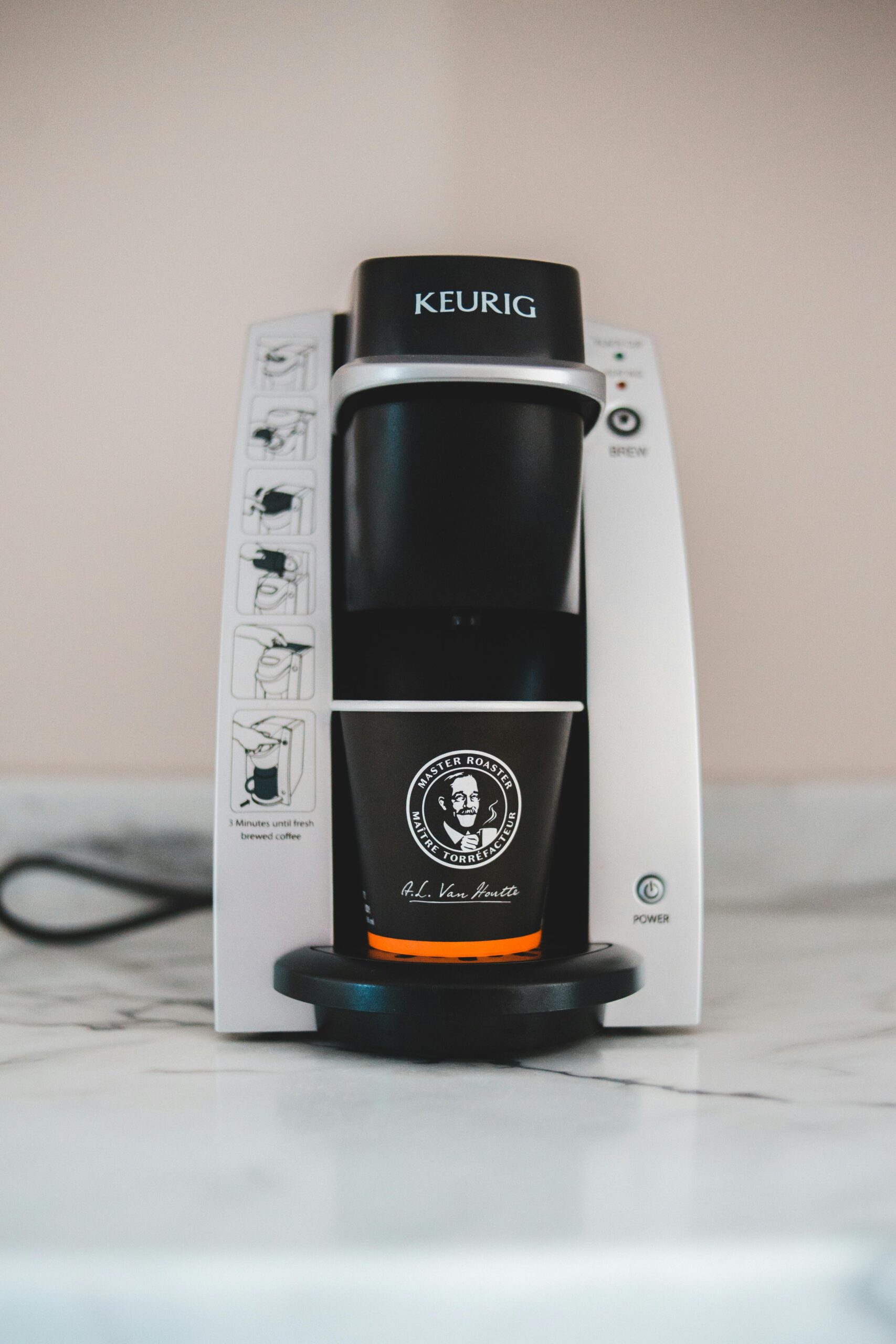 Automatic contemporary coffee machine with paper cup on marble table in light room